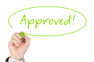 Hand writing the word "approved" for a mortgage refinance