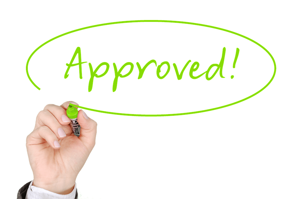 Hand writing the word "approved" for a mortgage refinance